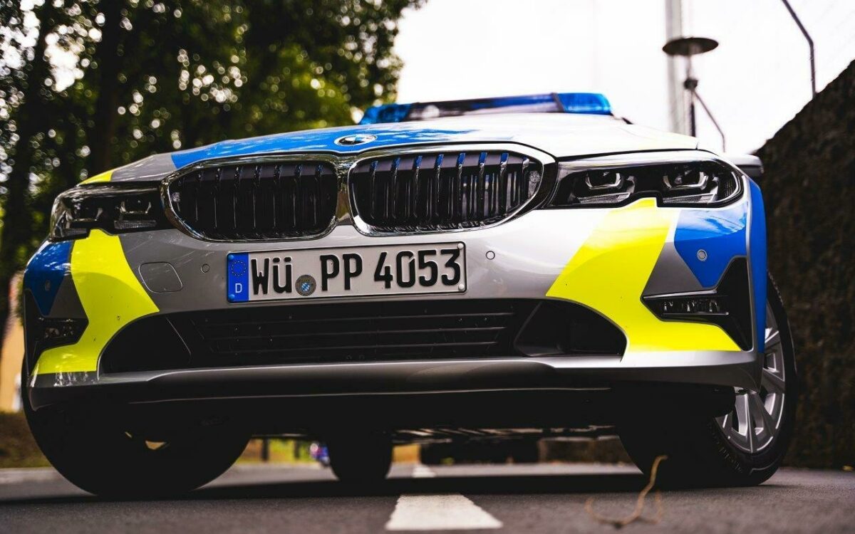Polizei im Einsatz das Polizeiauto mit Blaulicht am Straßenrand im Fokus die Stoßstange Polizei im Einsatz das Polizeiauto mit Blaulicht am Straßenrand im Fokus die Stoßstange
